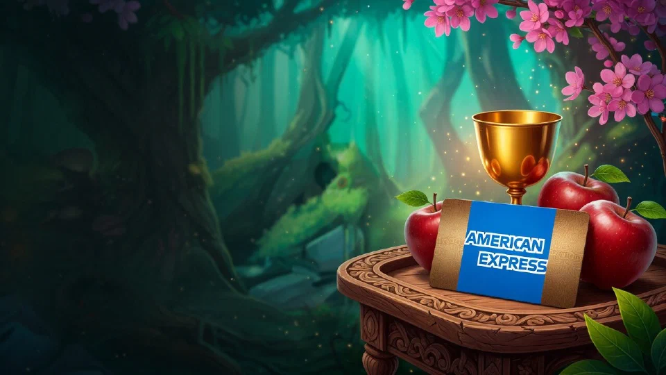 American Express logo on a payment card on a carved wooden tray beside a golden goblet and red apples